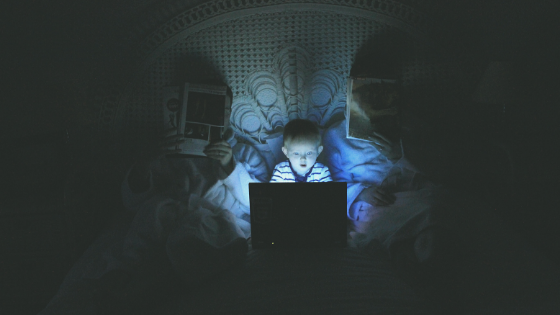 child in bed with blue light screen that is bad for sleep hygiene