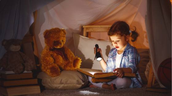 child reading with flashlight