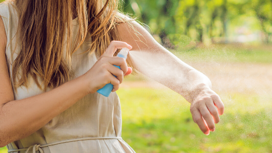 woman spraying natural bug spray made with tea tree oil