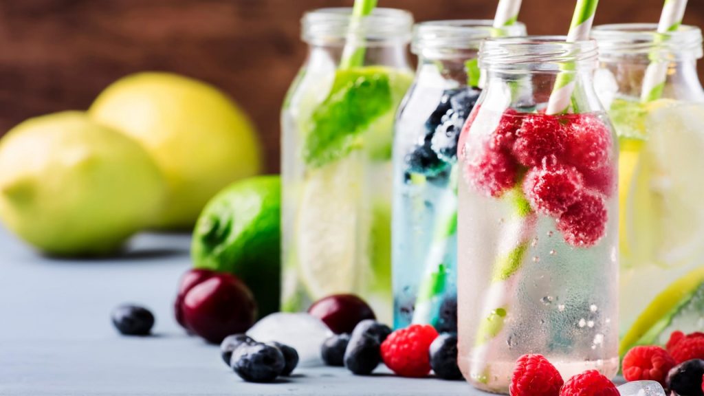 jars of fruit infused water with green paper straws - a great summer drink