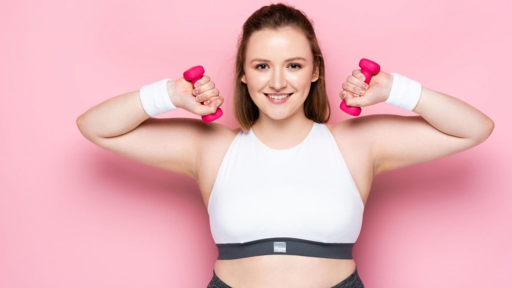 strong, smiling woman holding light weights