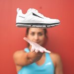 woman tossing workout shoe in air