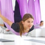 woman practiving aerial yoga in a purple hammock