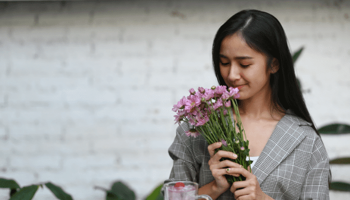 woman smelling flowers after regaining sense of smell