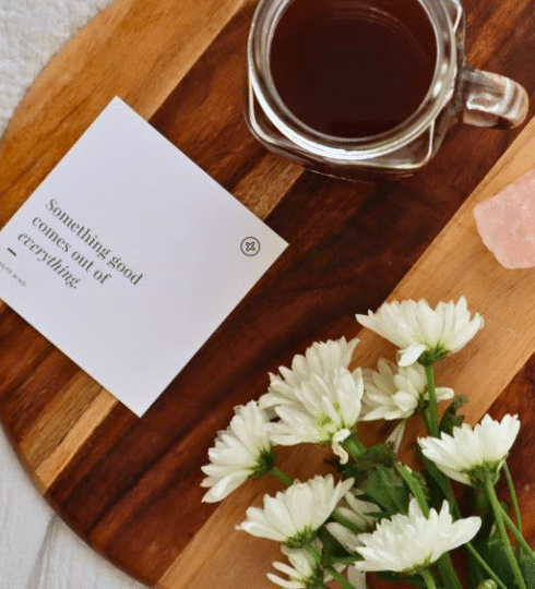 Wooden tray with positive affirmation note and a cup of tea and flowers