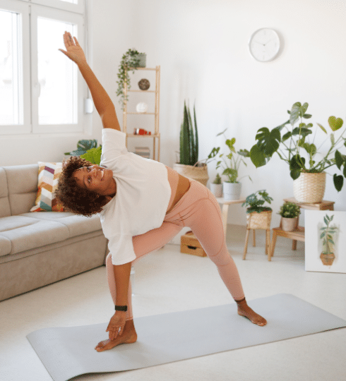 health blog woman in white tshirt and pink leggings do yoga in her living room